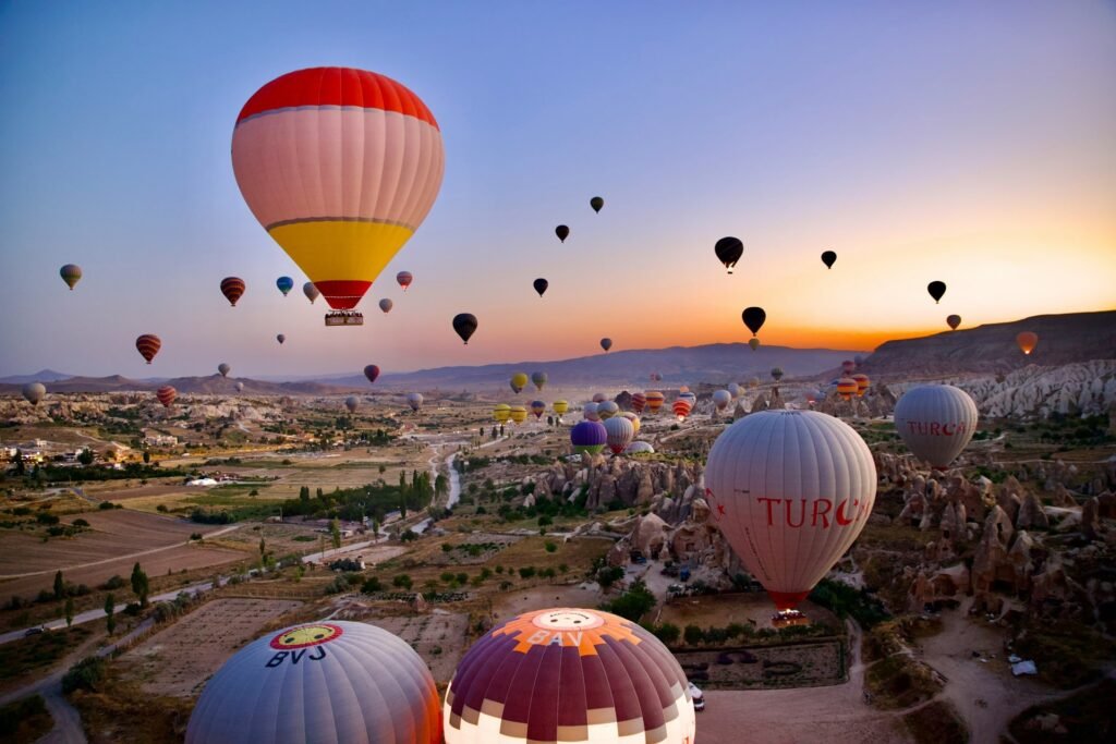 Hot air balloons floating over the rocky landscape of Cappadocia at sunrise.