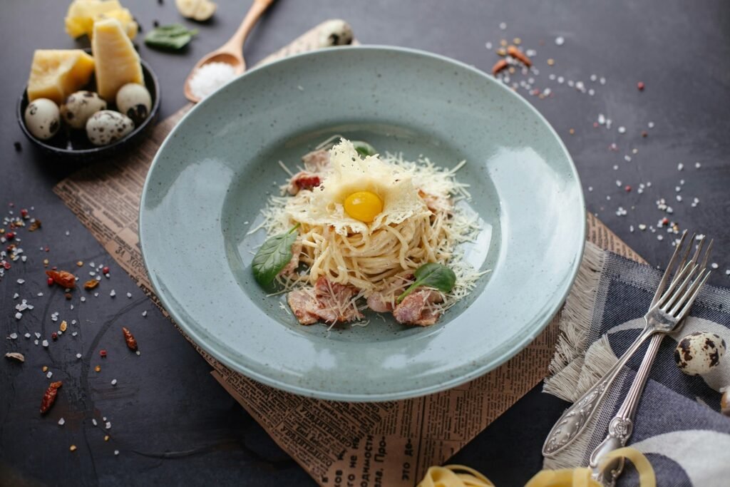 A bowl of spaghetti carbonara with grated cheese, pancetta, and a raw egg yolk on top.