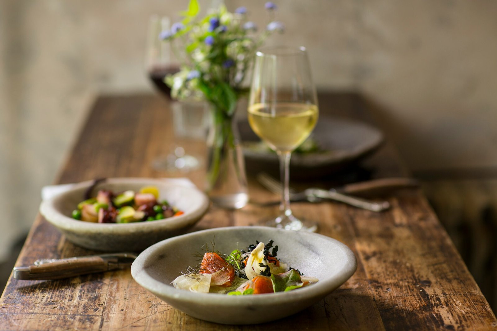 A plate of Italian food served on a table next to a glass of white wine.