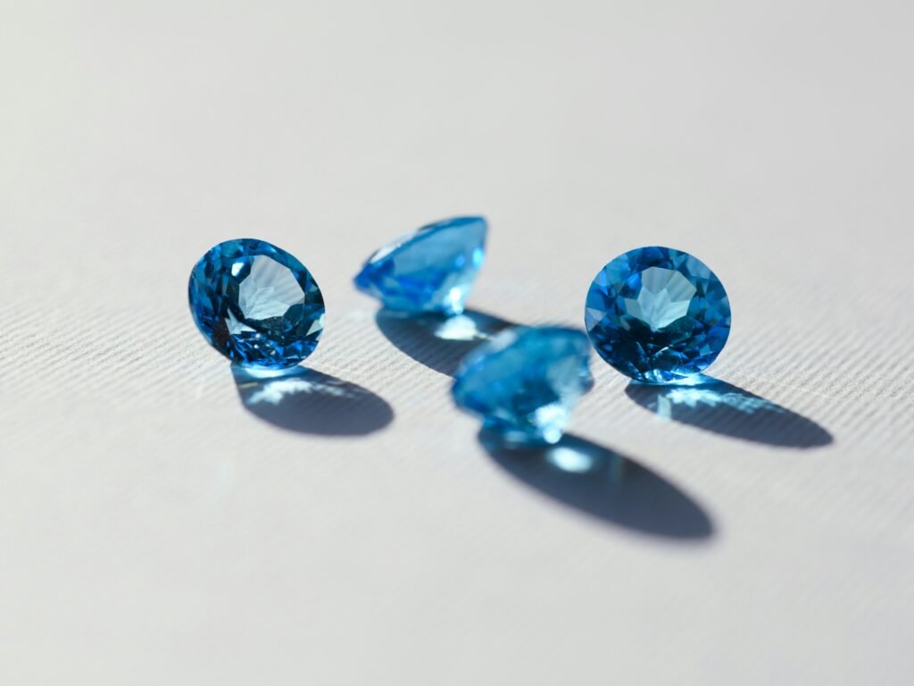 Four round-cut blue gemstones resting on a light surface with soft shadows.